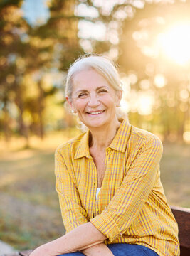 Portrait of an elderly woman outdoors. Happy senior woman sitting on a bench in park