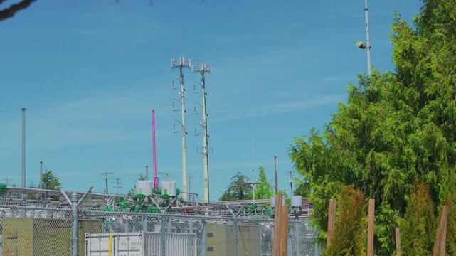 Electrical substation with cellular towers under clear blue sky