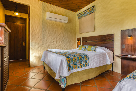 Rustic hotel bedroom interior with patterned bed runner