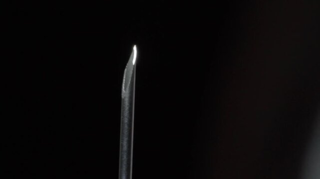 Macro close up of hypodermic needle tip highlighting sharp bevel and metallic surface. Detailed medical footage showcasing injection equipment, healthcare instrument and precision