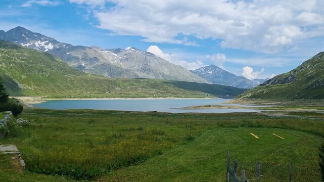 Picturesque high-altitude view of Lago di Montespluga near Spl&uuml;gen Pass, Italy, featuring a pristine alpine reservoir surrounded by rugged mountain under warm evening light, beauty of Italian Alps