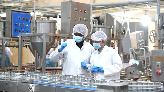 Quality control checking canned fish production process in seafood processing factory. Food safety inspection, quality assurance, hygiene standards, manufacturing, industrial food production.