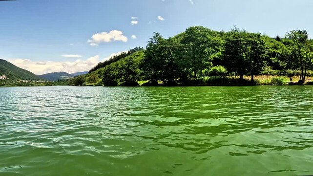Slow-motion navigating POV in a lake surrounded by hills. Lake Serraia is located on the Pin&eacute; plateau, exactly in Baselga di Pin&eacute; in the province of Trento, Trentino