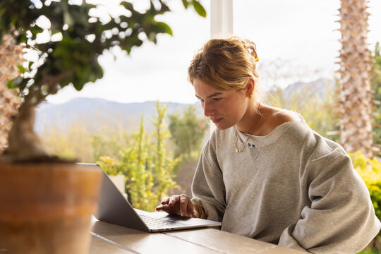 young woman using laptop computer on outdoor patio