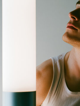 Light box portrait of male shoulder and jaw beside bright lamp soft glow clean gray background calm minimal studio lighting