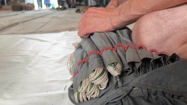 Close-up of the inspection of the stacked dome and parachute lines. The final stage of preparing the parachute system before performing the jump.
