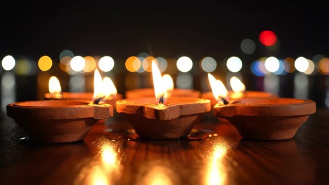 Close-up of burning clay lamps on wooden surface.