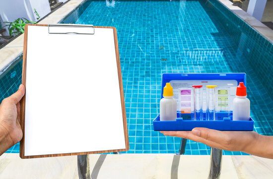 Swimming pool water tester in girl hand with report paper on wooden clipboard over clear swimming pool water background, pool service and maintenance