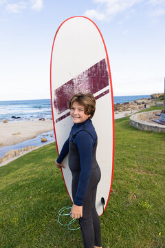 portrait of 13 year old boy smiling holding his surfboard