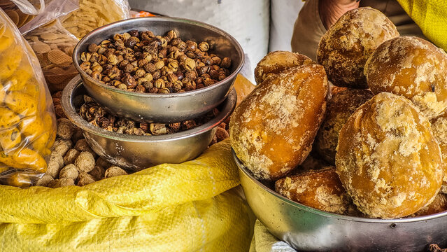 Natural jaggery blocks displayed beside dried shikakai (Acacia concinna) pods, known as "fruit for hair" and widely used in traditional Indian Ayurvedic medicine and herbal hair care