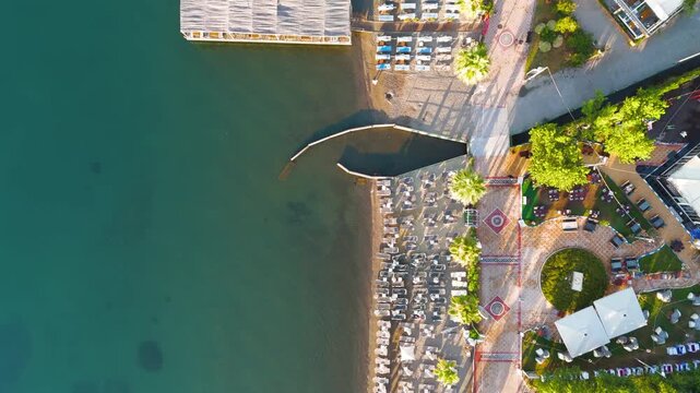 Marmaris, Turkey. Top-down aerial view of a geometrically aligned beachfront with rows of sun umbrellas, a patterned promenade, and resort hotels along the calm morning sea. Aerial View, HEAD OVER SH
