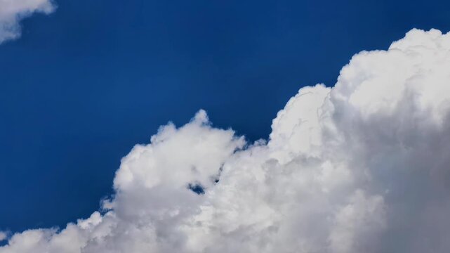 Towering cumulus clouds build against a blue sky in time lapse, dramatic cloud formation, atmospheric motion, natural weather, scenic background.