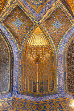 Gilded muqarnas niche inside Ak Saray Mausoleum in Samarkand with intricate blue, gold tilework. Ornate interior detail of Timurid architecture in Uzbekistan, ideal for travel, cultural publication.