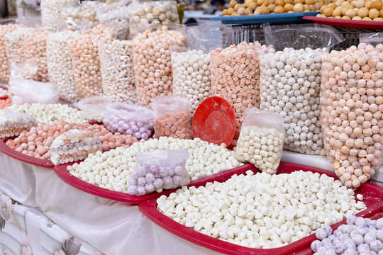 Traditional dried cheese - kurt dairy balls displayed at an oriental bazaar in Bukhara, Uzbekistan. Colorful assortment of confections in bags and trays at a market stall, ideal for travel and food.