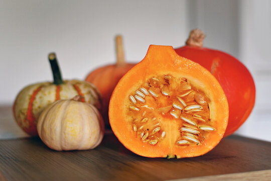 Halved Hokkaido pumpkin showing seed with other pumpkins in background