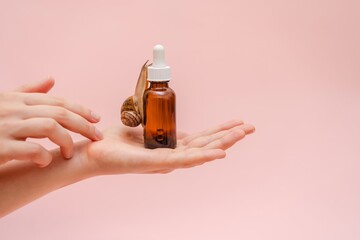 Cosmetic brown bottle with snail in elegant hand. Concept of skin care product, spa, luxury, natural beauty © Antonio