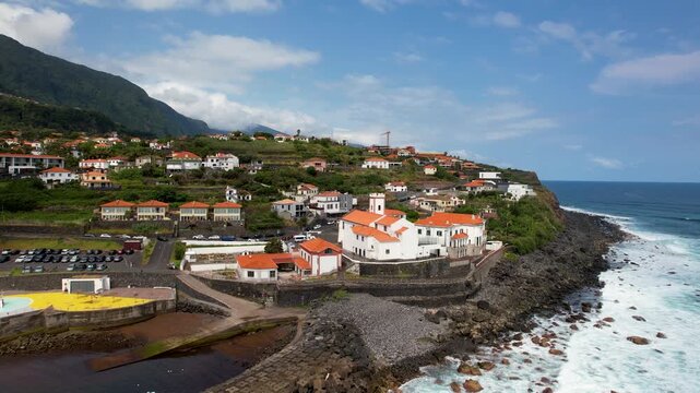 Ponta Delgada Madeira coastal village drone backward flight and ascent from the historic church towards the ocean revealing natural swimming pools