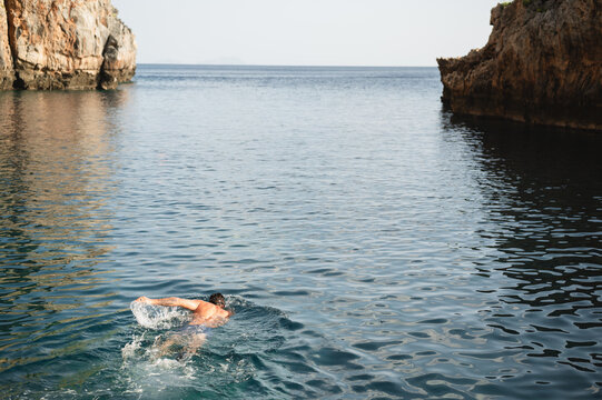 Swimmer crossing a calm rocky cove at Kalypso Beach with copy space