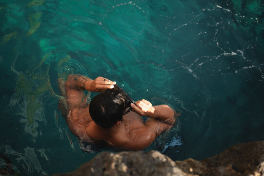 Man preparing snorkeling gear in clear water at Kalypso Beach in Crete