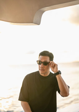 Man on a boat adjusts sunglasses at golden hour