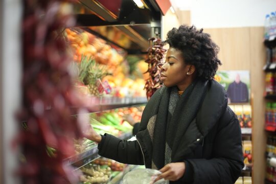 Young woman picking fresh vegetables at a grocery store