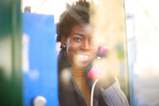 Happy woman smiling in a vintage phone booth