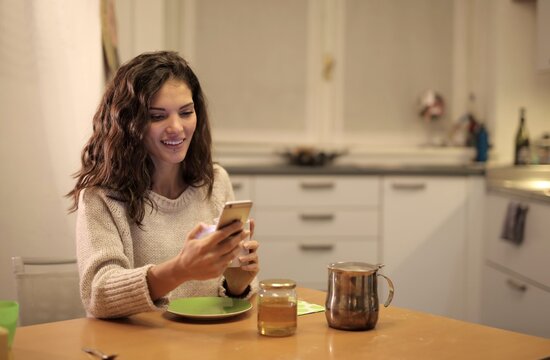 Young woman smiling while looking at her phone at home