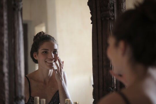 Happy young woman doing her morning skincare routine