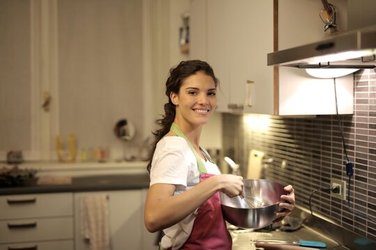 Smiling woman whisking ingredients in a kitchen bowl