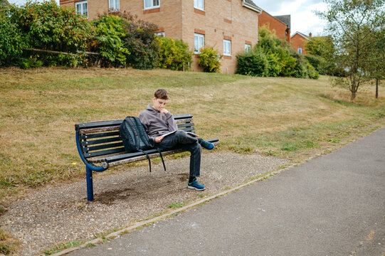Boy sitting on a park bench with an open notebook