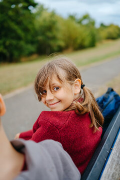 Smiling girl sitting on a park bench with brother