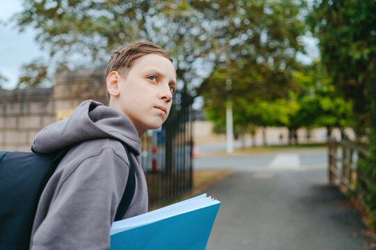 Boy holding school notebooks near the entrance to a school
