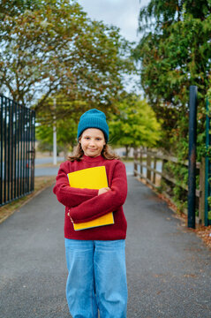 Girl holding school notebooks near the entrance to a school