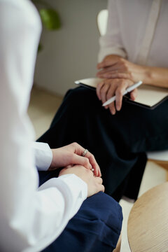 Vertical shot of middle aged woman consulting client, listening and taking notes during therapy session, conveying mental health support. Ideal for counseling, wellness, healthcare marketing