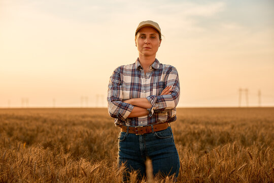 Female farmer standing confident in golden wheat field