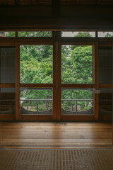 Fototapeta premium Traditional Japanese interior framing a lush green garden through wooden sliding screens and windows
