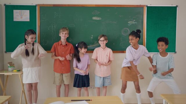 Group of diverse school kids dancing in front of classroom at primary school.
