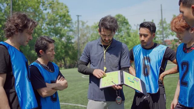 Football coach explaining game strategy to team player during training. 