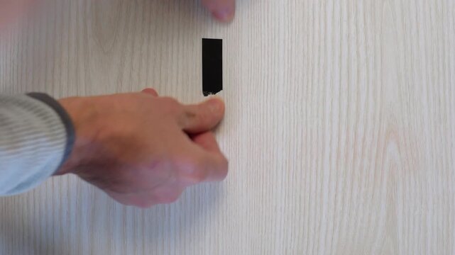 Hands assembling cross black tape marker, creating orientation point for stage positioning, methodical placement on wood surface with studio prep and precise measurement focus