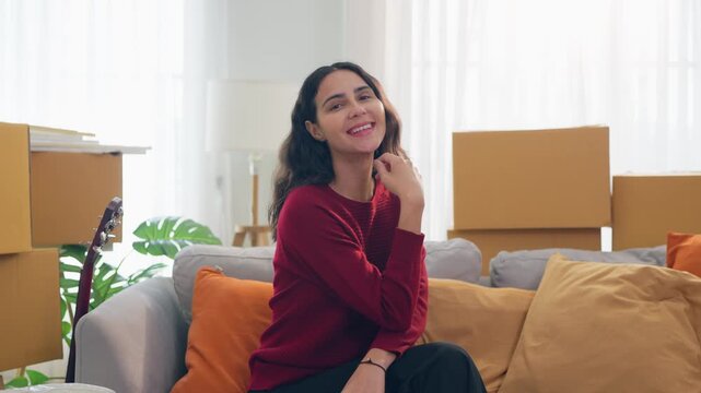 Portrait of young Hispanic woman look at camera while moving into a new home. 