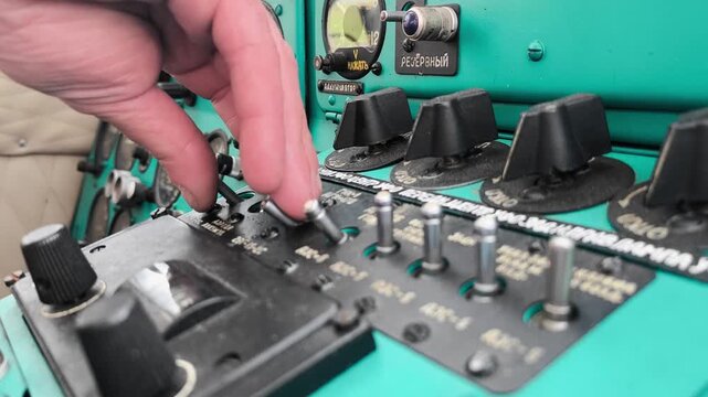 Close-up of the pilot's hand switching the flight switches on the control panel of the An-2 aircraft during pre-flight training.
