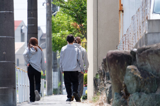 グレーの服を着た男女３人の後ろ姿