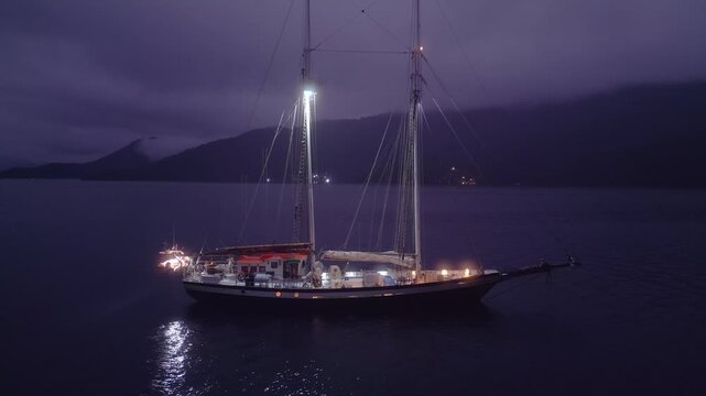 Big expeditional sailing boat anchored in the calm sea at night. Drone night shot