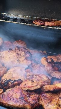 Nottingham England UK. 11.07.2026. Video. Tender marinated pork steaks sizzle and char on a black metal grill grate, with smoke rising around them