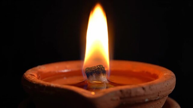 Extreme close-up of a single burning clay diya flame.