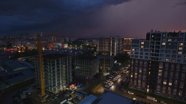 Lightning flashes over the buildings in a city. Rain and thunder storm over the city.