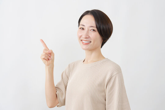 左を指差す笑顔の女性　ミドルエイジ　白背景