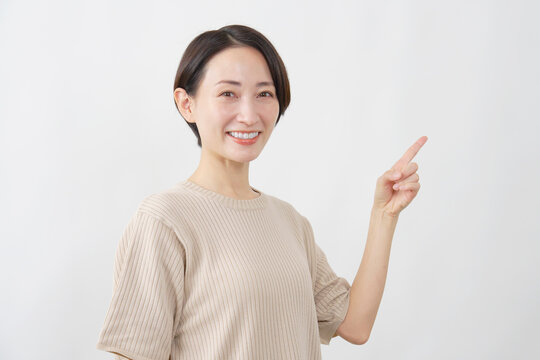 右を指差す笑顔の女性　ミドルエイジ　白背景