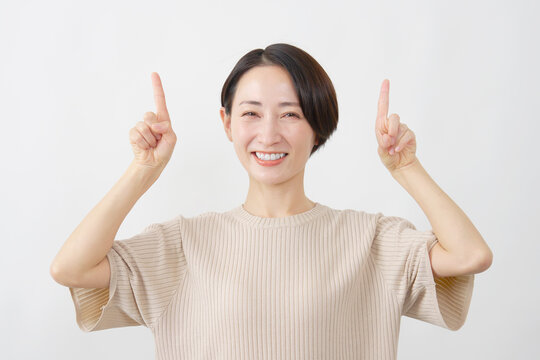両手で上を指し示す女性　ミドルエイジ　白背景