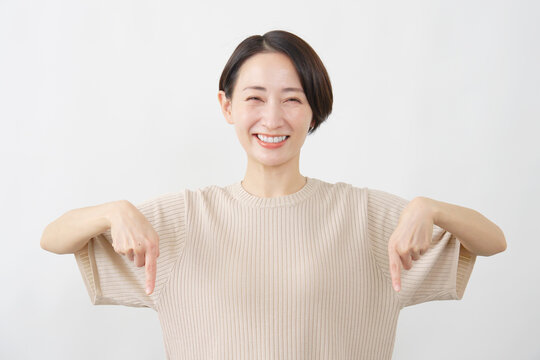 両手で下を指し示す女性　ミドルエイジ　白背景